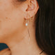 Close-up of a person wearing gold earrings and a necklace with a blurred background