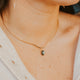 Close-up of a person wearing a gold necklace with a pendant.