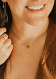 Close-up of a person wearing a gold necklace with a small pendant.