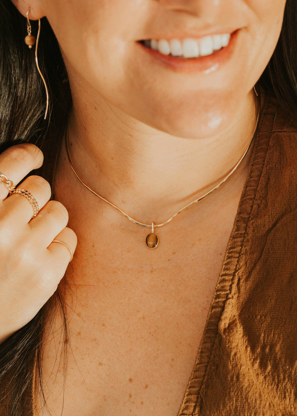 Close-up of a person wearing a gold necklace with a small pendant.