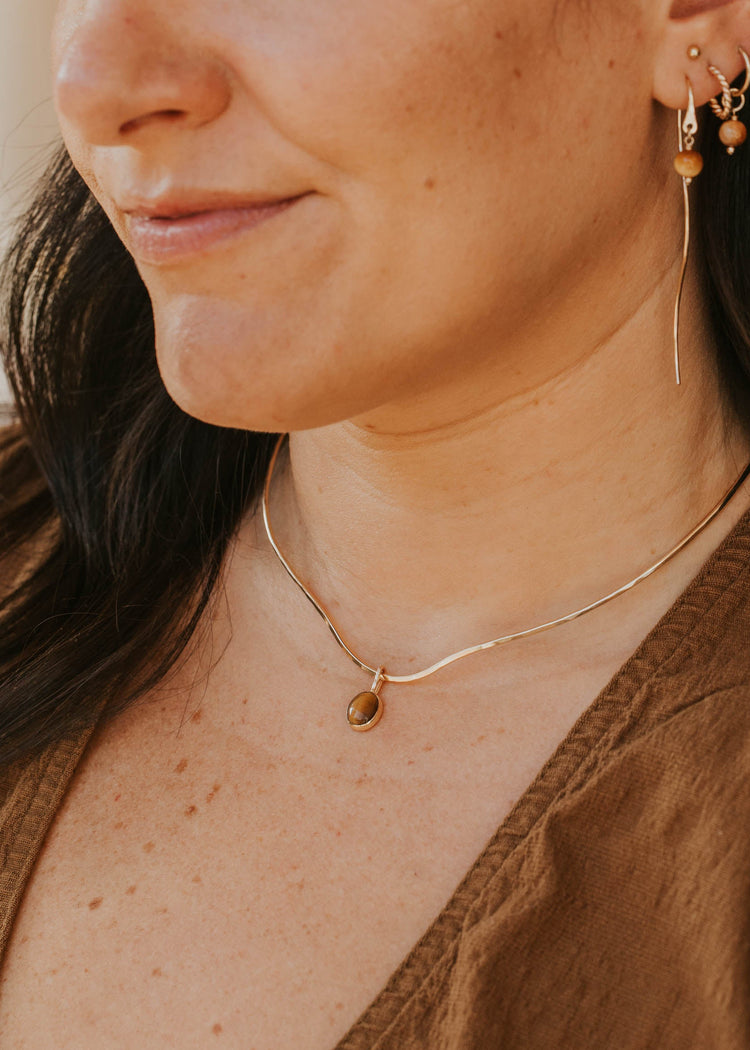 Close-up of a woman wearing gold earrings and a necklace with a blurred background
