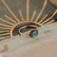 Decorative ceramic plate with sunburst design and central gemstone on a textured surface.
