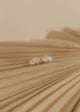 Pair of gold earrings on a textured beige surface