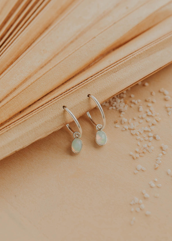 Silver earrings with gemstones on a textured beige surface