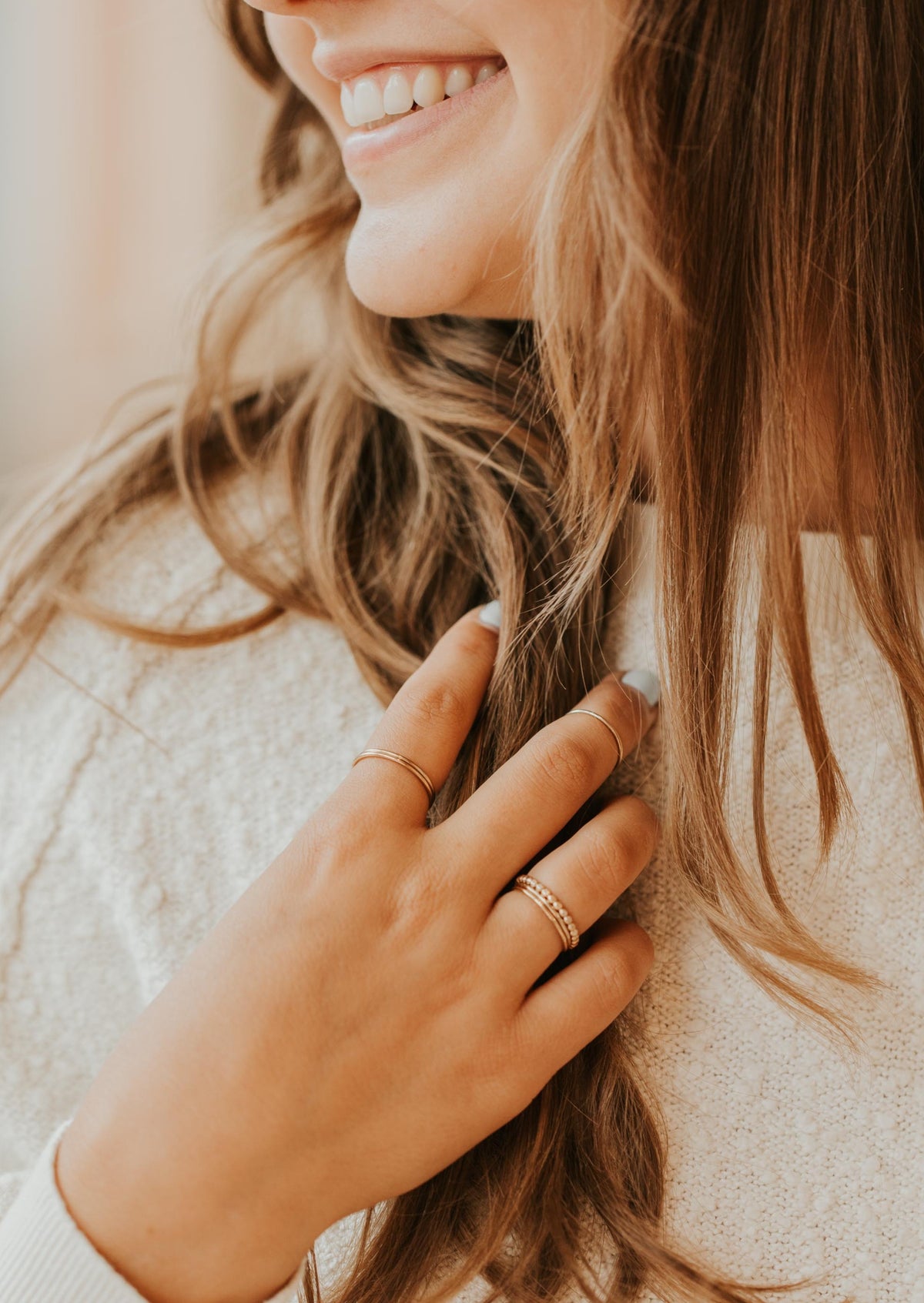 Gold Teeny-Tiny stackable ring being held, styled with a textured ring to create a ring stack by Hello Adorn.