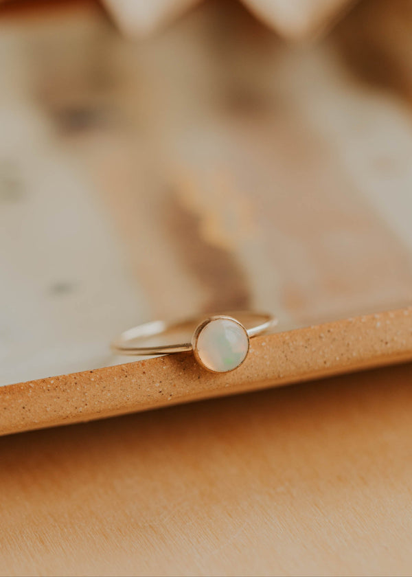 Gold ring with a round stone on a beige surface
