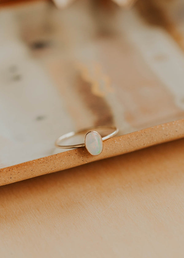 Silver ring with an oval stone on a beige surface
