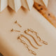 Gold jewelry pieces on a beige surface with a textured background