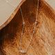 Delicate gold necklace with small gemstones on a wooden surface