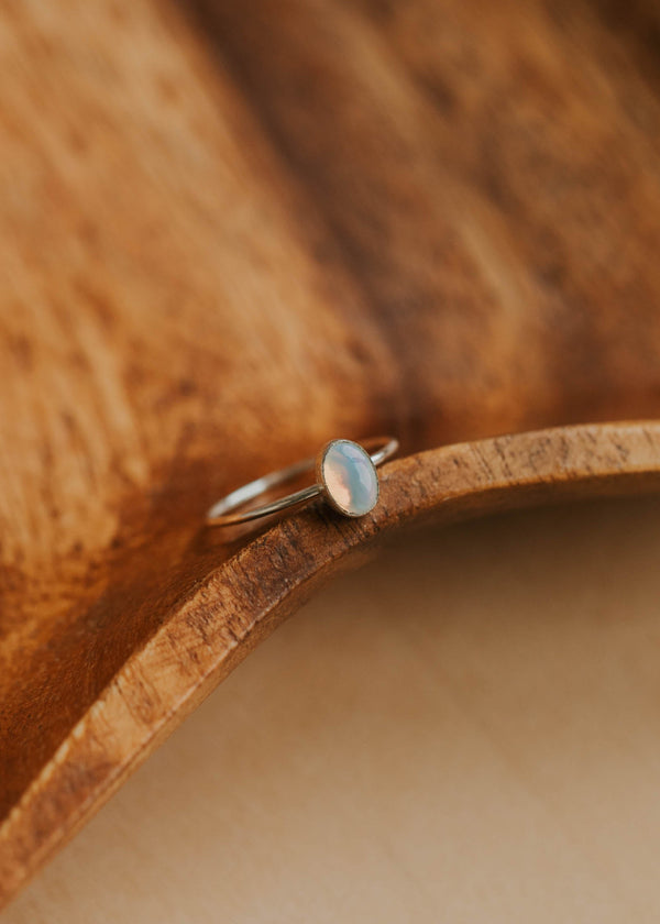 Silver ring with a blue stone on a wooden surface
