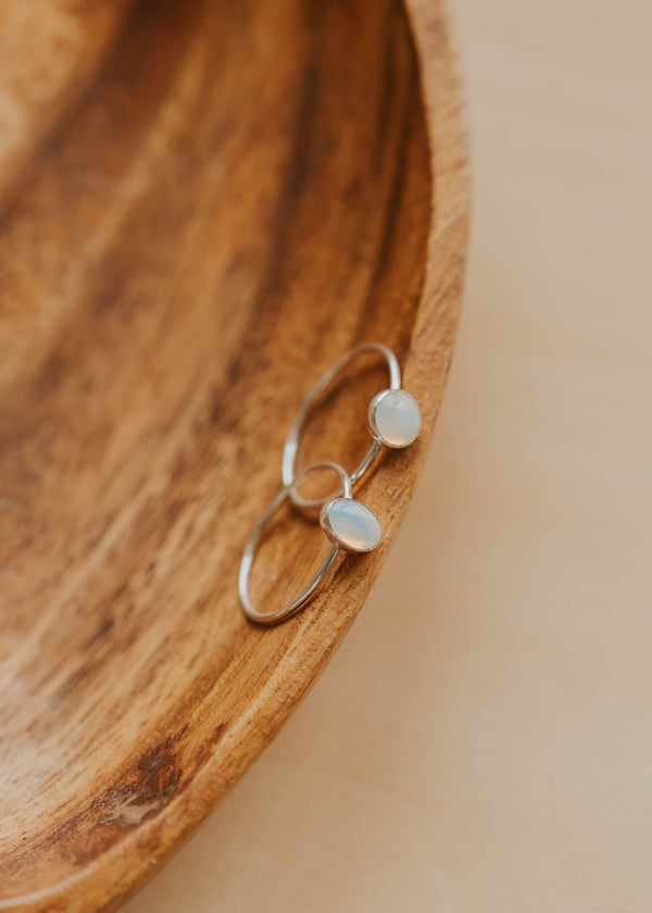 Silver ring with two circular stones on a wooden surface