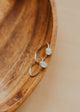Silver ring with two circular stones on a wooden surface