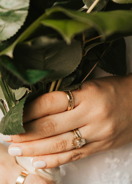 Close-up of hands holding a bouquet with gold rings on fingers