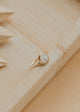 Gold ring with a stone on a textured wooden surface
