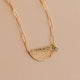 Gold necklace with a half-circle pendant on a beige background