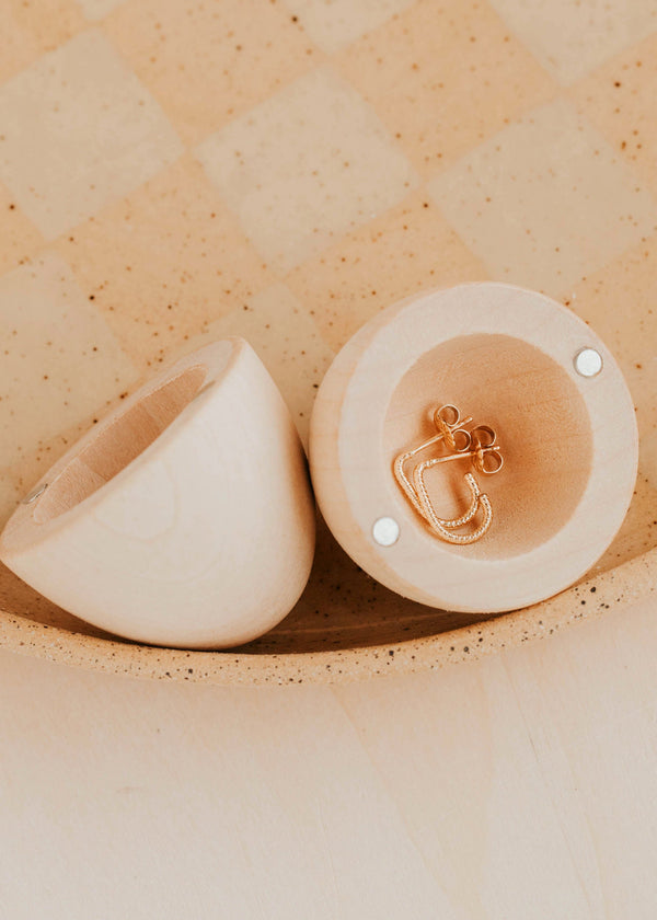 Wooden egg with jewelry inside on a textured beige surface