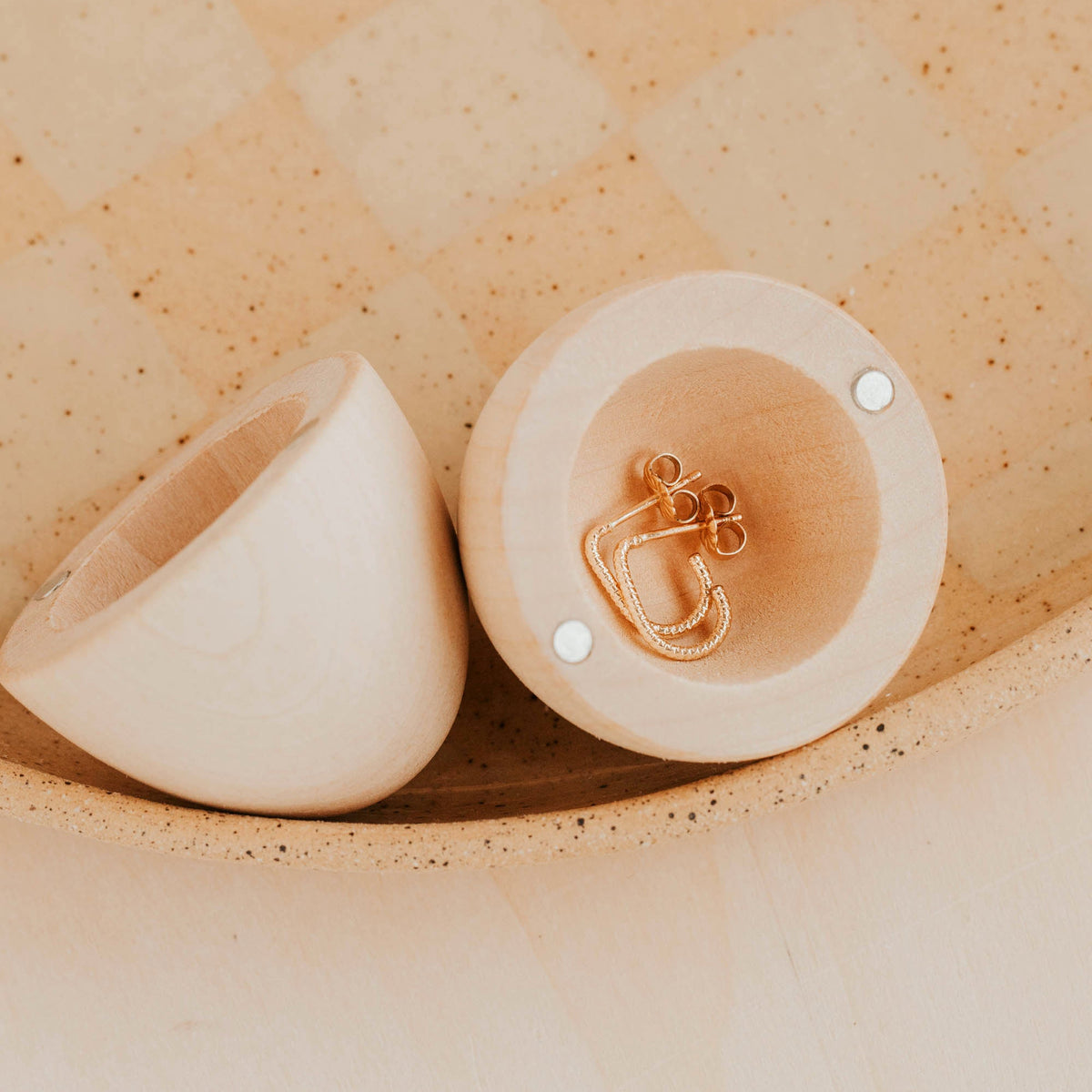 Two wooden eggs on a textured beige surface