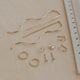 Set of gold jewelry pieces on a beige surface with a ruler for scale.