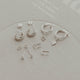 Set of silver earrings on a clear stand with a light gray background