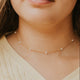 Close-up of a person wearing a delicate pearl necklace with a blurred background