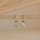 Gold earrings with round stones on a beige background