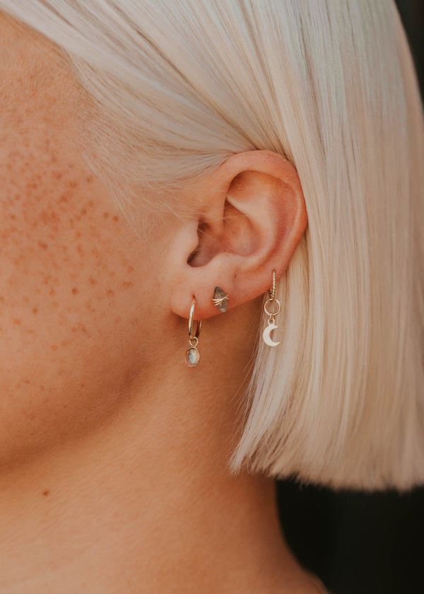 Close-up of an ear with multiple earrings against a blurred background