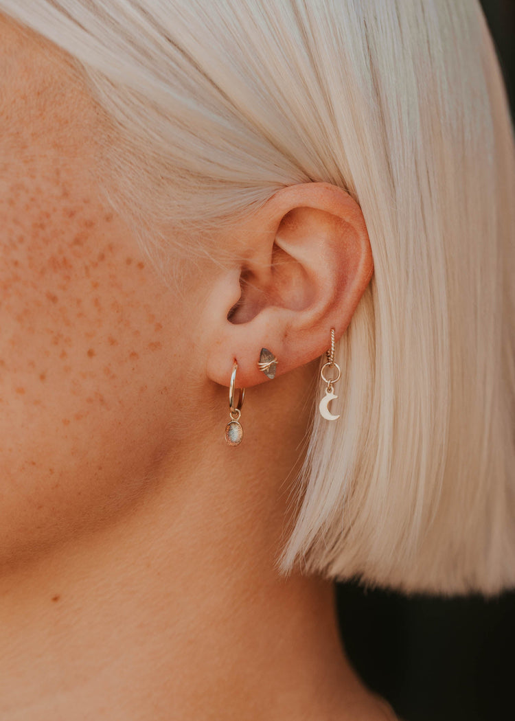 Close-up of an ear with multiple earrings against a blurred background