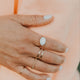 Hand wearing multiple rings on a soft peach background