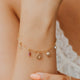 Gold bracelet with charms on a wrist against a blurred background