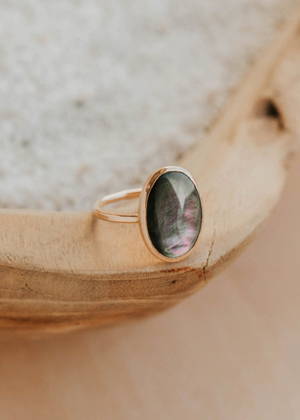 Gold ring with a green stone on a wooden surface