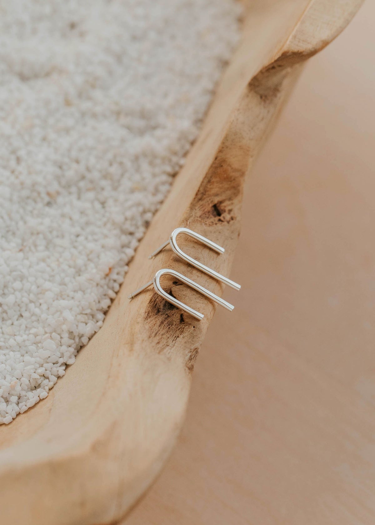 Silver ear cuff on a wooden surface with sand in the background
