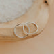 Two silver rings on a wooden surface with a neutral background