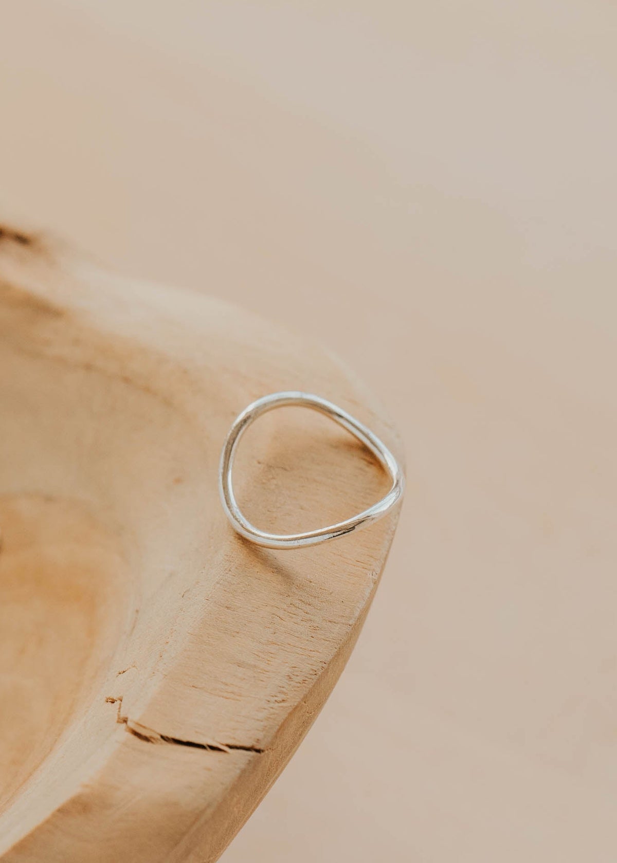 Silver ring on a wooden surface with a neutral background