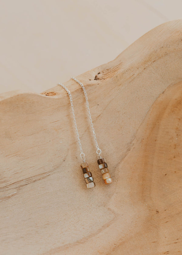 Silver earrings with small beads on a wooden surface
