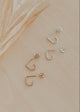 Set of gold and silver earrings on a beige surface with a leaf