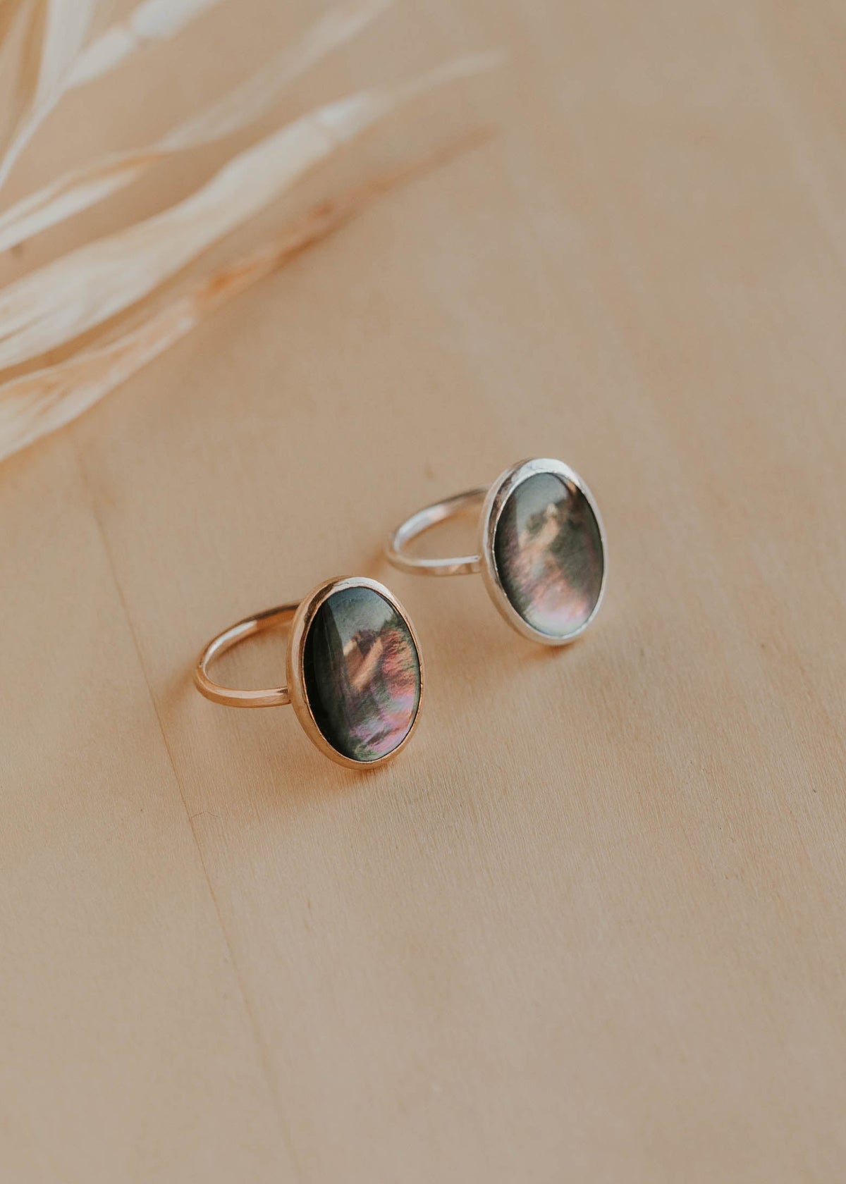 Two gold rings with circular gemstones on a beige background