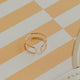 Gold ring on a striped surface with a product box in the corner