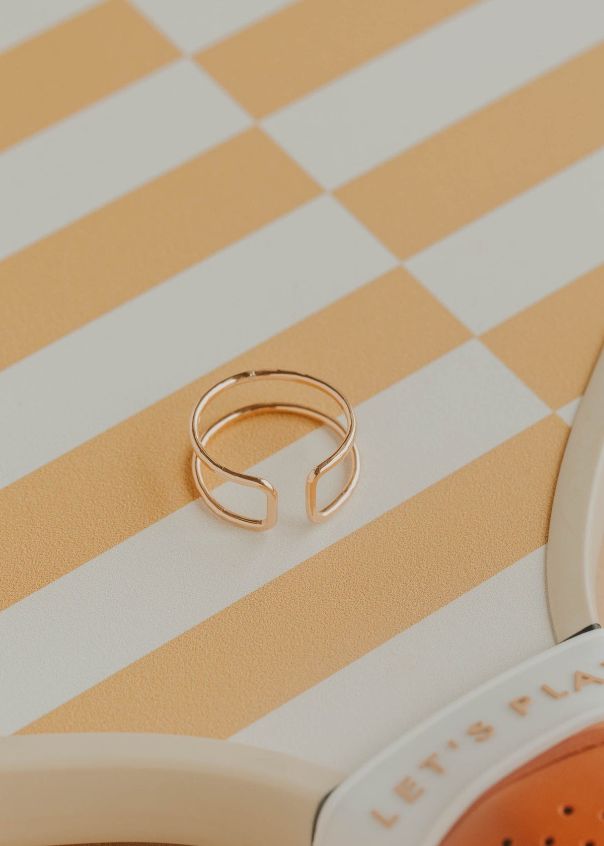 Gold ring on a striped surface with a product box in the corner