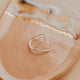 Heart-shaped silver ring on a beige ceramic dish