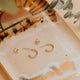 Gold earrings on a decorative tray with a soft focus background