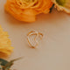 Heart-shaped gold ring on a light surface with yellow flowers
