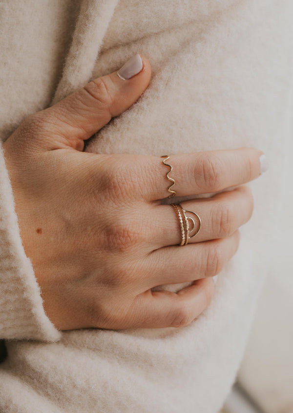 A three ring stack featuring a squiggle ring, a beaded ring, and a rainbow ring with wire added to create a wire wrapped ring styled by Hello Adorn.