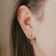 Earrings with hanging chain in Mini Annex Style by Hello Adorn styled with a horseshoe threader earring, gold circle dot stud, and a tiny hoop earring in 14k gold fill earrings.