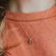 A custom necklace pendant with an evergreen tree stamped onto this gold necklace by Hello Adorn.