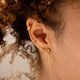 A gold earring stack with a twist earring, a dangly earring as a chain earrings design, and two ear cuffs in the Ear Cuff duo style by Hello Adorn.
