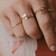 A simple jewelry ring stack styled with 2 beaded ring and hammered textured jewelry, an open ring in the Sonder design, and a rainbow ring with wire wrapping in 14k gold fill by Hello Adorn.
