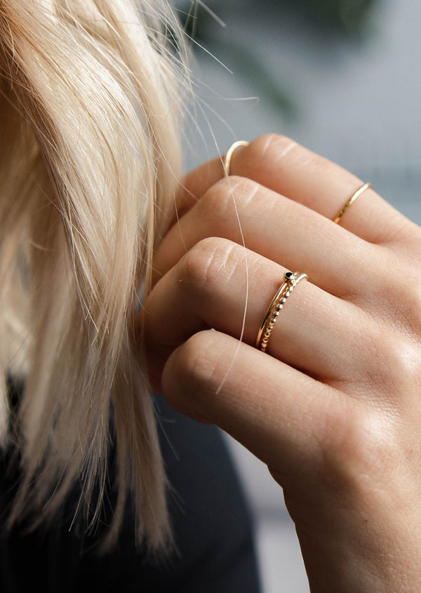 A beaded ring show in a ring stack styled with a gemstone ring, a thin gold ring, and an above the knuckle ring by Hello Adorn.