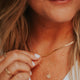 Model is wearing tiny gold initial necklace styled with a herra layering chain by Hello Adorn.