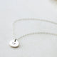A silver custom necklace pendant created as a heart necklace that includes a symbol stamped on jewelry by Hello Adorn.