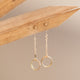 Drop earrings from Hello Adorn in the Monday Backdrop style where a stud earring is attached to a chain drop earring with a circle attached to the end of the chain.